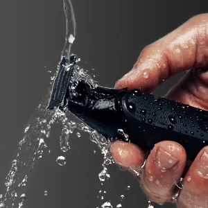 Braun trimmer being rinsed under running water, demonstrating its waterproof design.