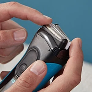 Braun shaver head being removed for cleaning or replacement.