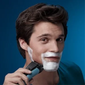 Braun shaver being used by a man with shaving cream on his face.
