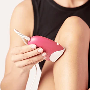 Braun IPL device being used on a woman's leg for hair removal.