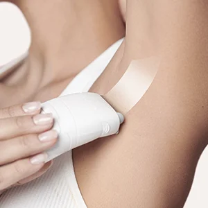 Braun Silk-épil epilator being used on an armpit with a strip of tape applied to the skin.
