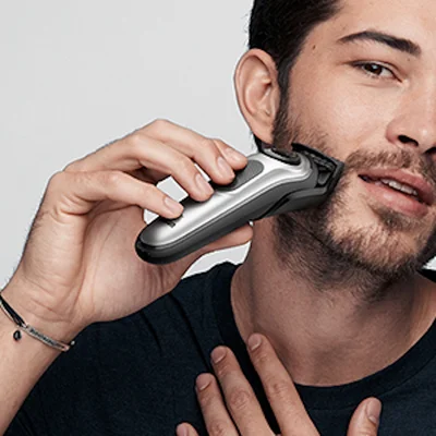 Braun shaver being used on a man's face to trim his beard.