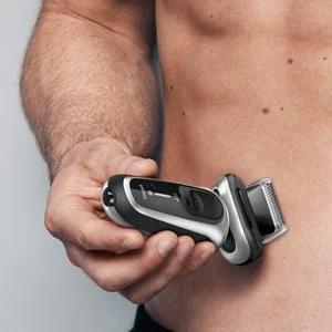 Braun Series 9 Pro electric shaver being held up to a man's torso, demonstrating its use.