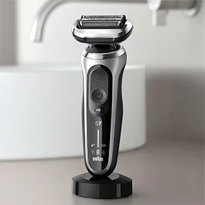 Braun Series 7 electric shaver on its charging stand, displayed in a bathroom setting.