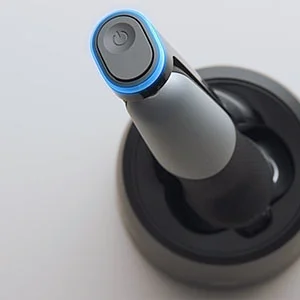 Braun toothbrush handle in charging base, showing the illuminated power button.