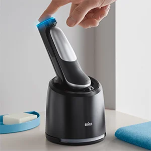 Braun shaver in a charging dock with a hand pressing the top of the shaver.