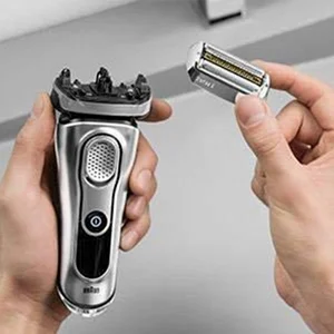 Braun electric shaver being held with a replacement shaver head, showing the head replacement process.