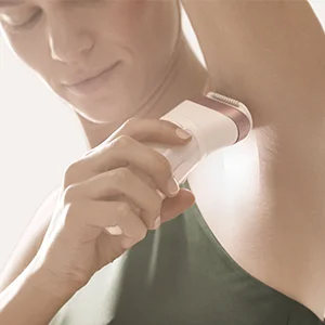 Woman using a Braun epilator under her arm, demonstrating hair removal.