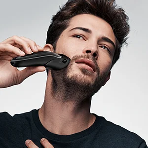 Braun shaver being used by a man to shave his beard.