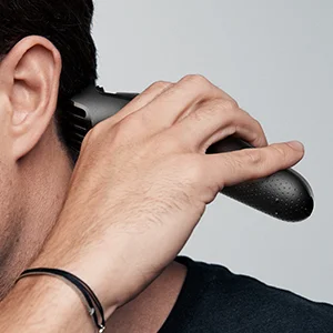 Braun trimmer being used to trim the back of a man's neck, demonstrating at-home hair maintenance.
