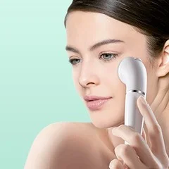 Woman using a Braun facial cleansing brush on her cheek for gentle exfoliation.
