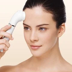 Braun cleansing brush being used on a woman's forehead.