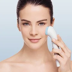 Braun cleansing brush being used on a woman's face, demonstrating its use for facial cleansing.