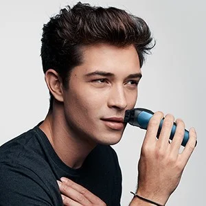 Braun shaver being used on a man's face, trimming his mustache.