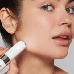 Braun device being used on a woman's face, emitting a soft light.