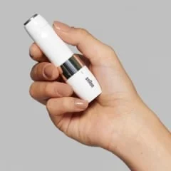 Braun Mini Hair Remover held in a hand, showcasing its compact, portable design.