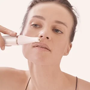 Braun facial hair remover being used on a woman's upper lip.