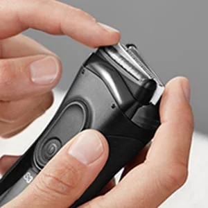 Braun shaver head being removed or attached by a person's fingers.