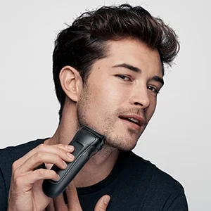 Braun electric shaver being used by a man to shave his beard.