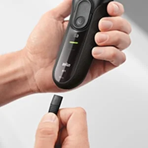 Braun shaver being held with a precision trimmer attachment being connected.