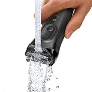 Braun shaver being rinsed under running water, demonstrating its waterproof design.
