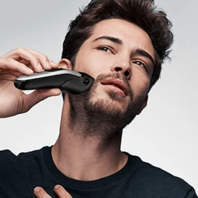 Braun beard trimmer being used on a man's face to trim and style his beard.