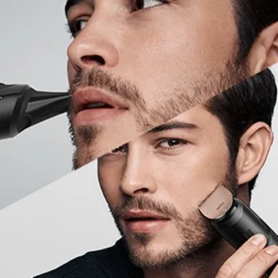 Braun beard trimmer being used to trim and style a man's beard.