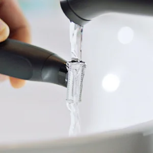 Image of the head of the trimmer being held under a flow of water from a tap