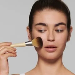 Woman applying makeup with a Braun makeup brush.