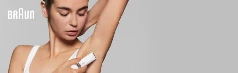Woman using a Braun hair removal device on her underarm.