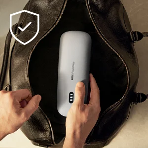 Braun PowerCase being placed in a dark leather bag, demonstrating its portability with a checkmark icon.