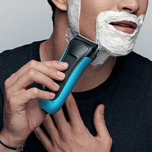 Braun electric shaver being used on a man's face covered in shaving cream.