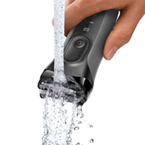 Braun trimmer being rinsed under running water, highlighting its waterproof design and easy cleaning.