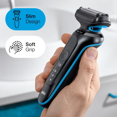 A hand holds a black and blue Braun electric shaver with graphics for Slim Design and Soft Grip, and text on the shaver reads EasyClean, S5, and BRAUN.