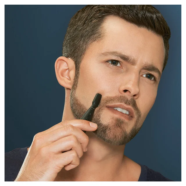 Man precisely shaping his beard with a Braun trimmer.