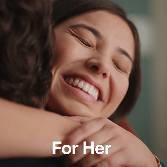 Braun for her - close up of woman's elated face as she is hugging a man who is only just in the left of the shot