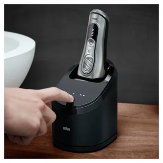 Series 9 Pro upisde down in a smartcare cleaning centre, with a hand turning it on - in a bathroom
